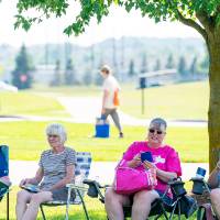 Man and three women sitting in lawn chairs under a tree